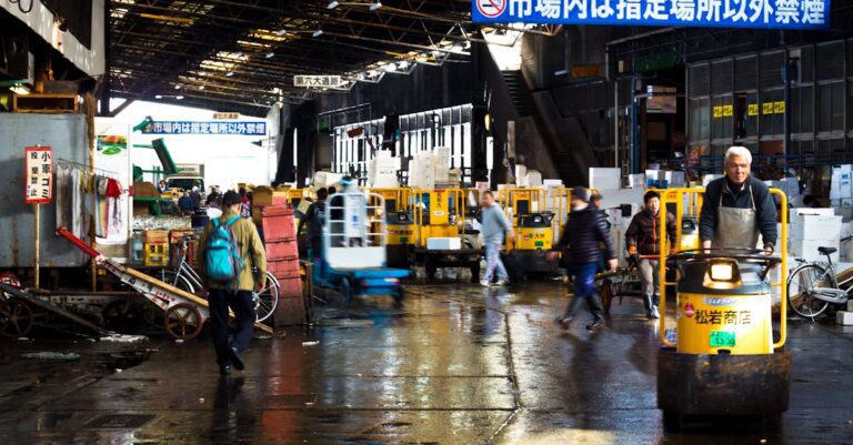 Lively scene at a Tokyo wholesale market featuring carts and transport vehicles.
